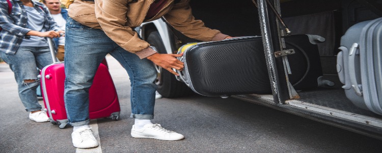 Charter bus passengers loading their luggage onto the bus